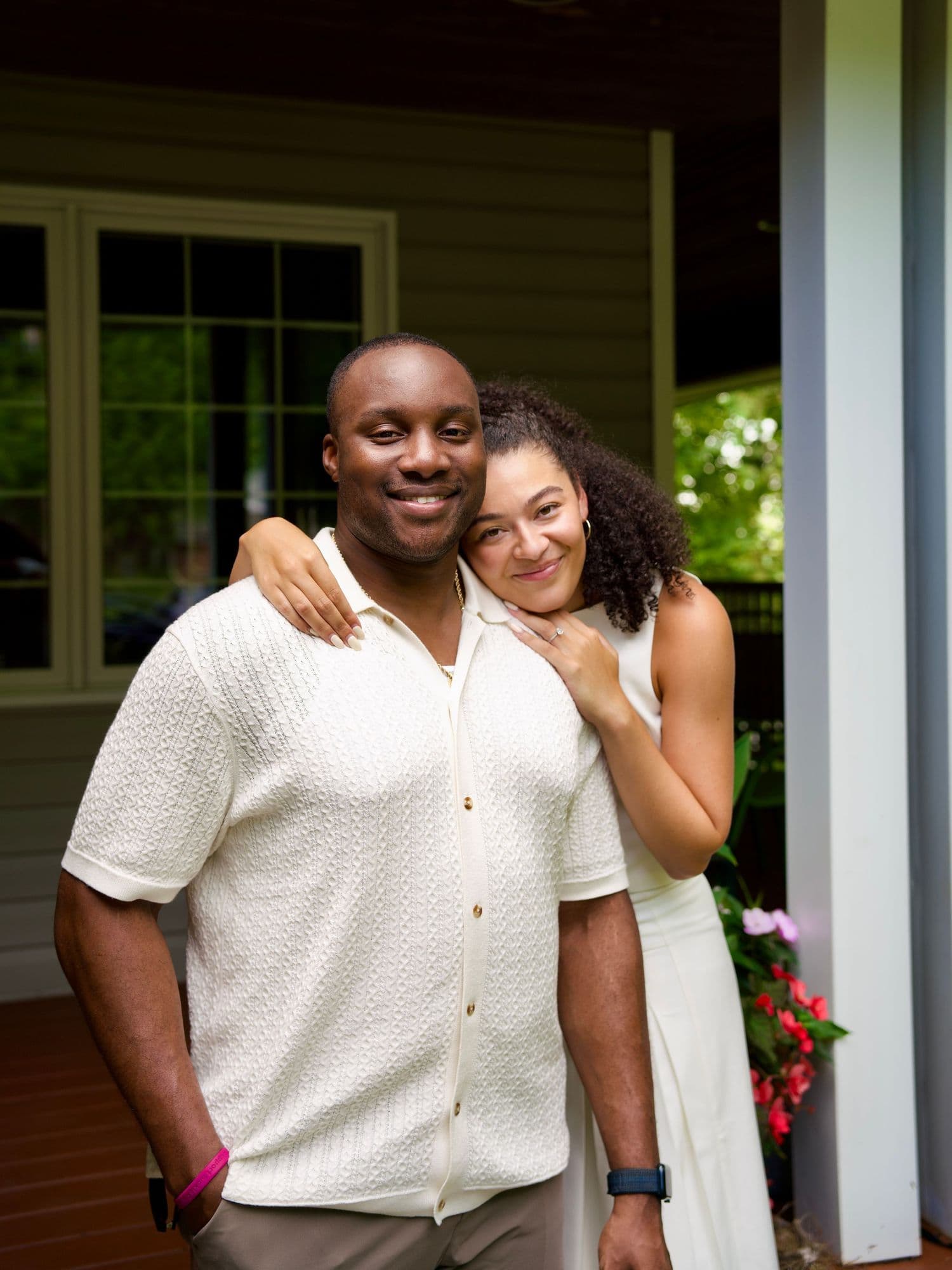 An engaged couple smiling together on a porch.