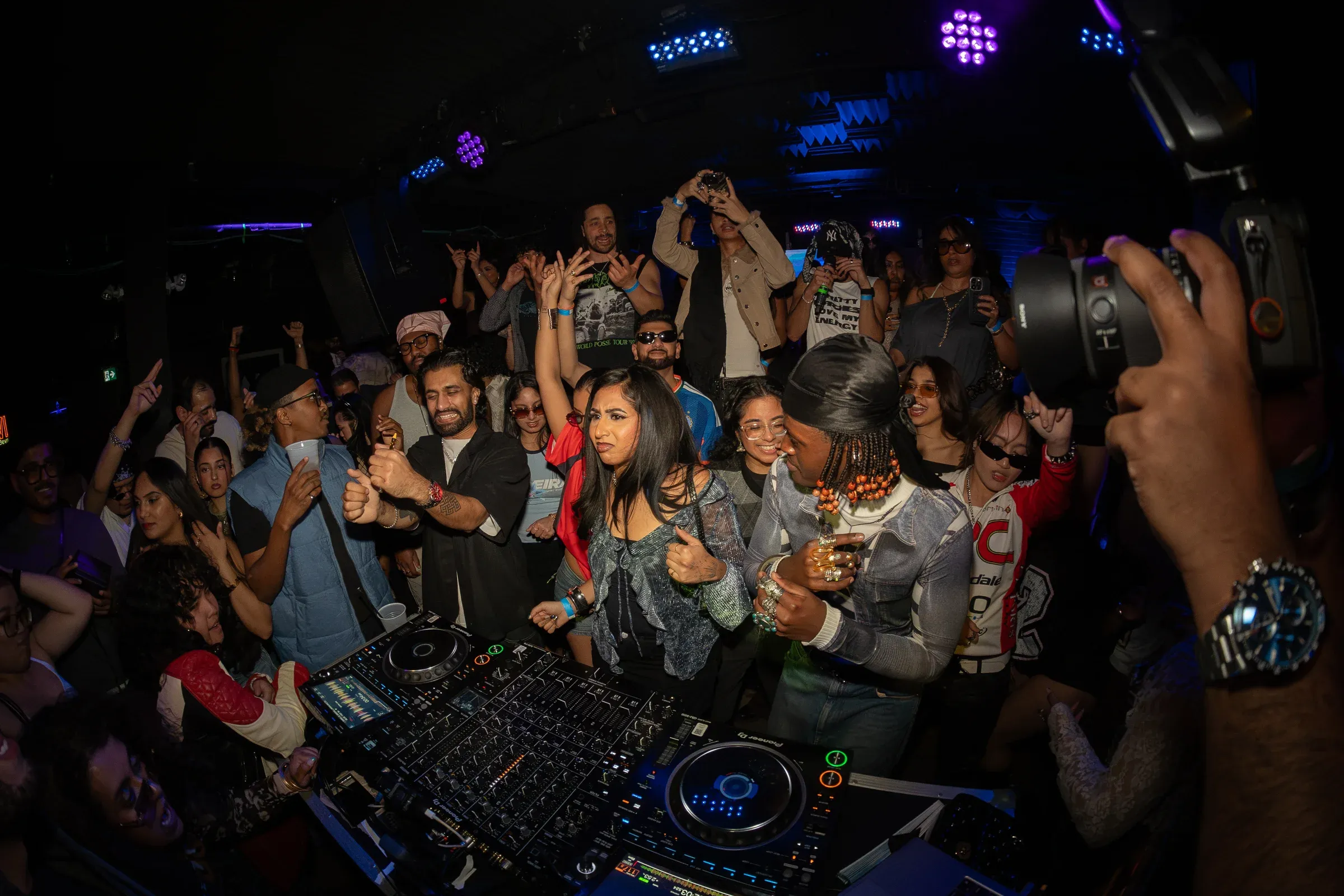 A packed dance floor around the DJ booth at MOOVE Toronto, hands up, stage lights overhead.