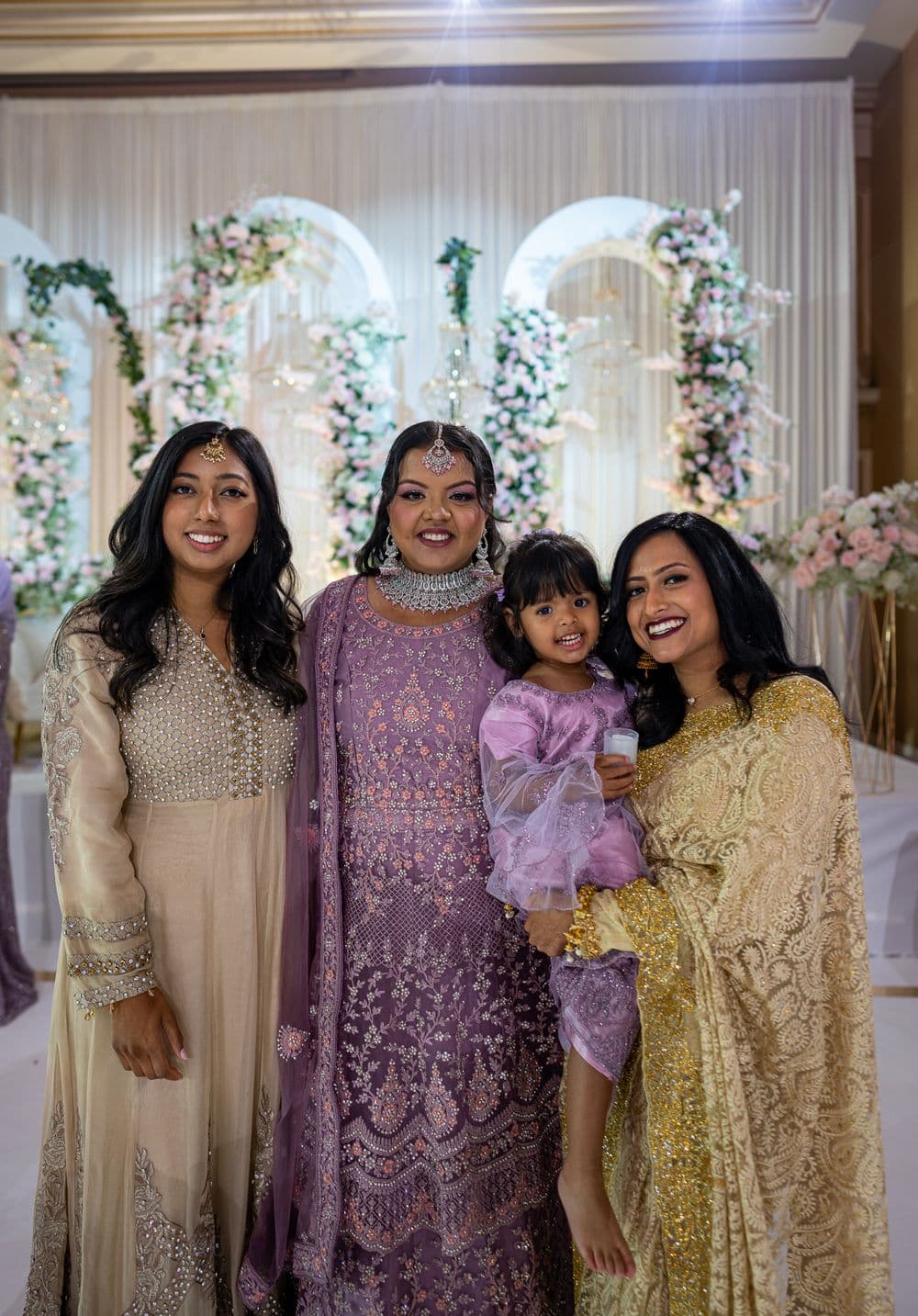 Family portrait at a wedding reception with floral stage details.