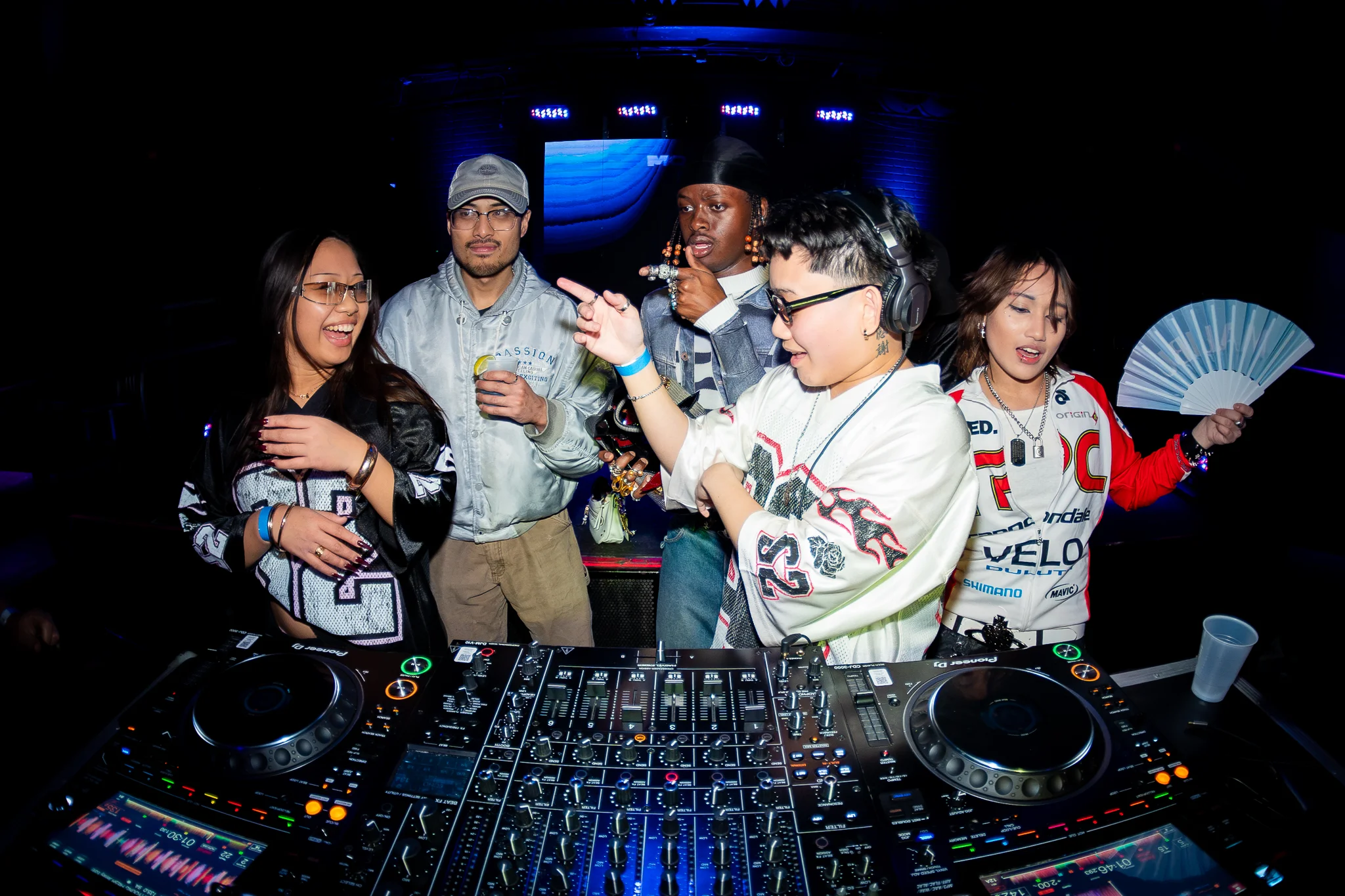 Friends gathered around the DJ booth under nightclub lighting at MOOVE.