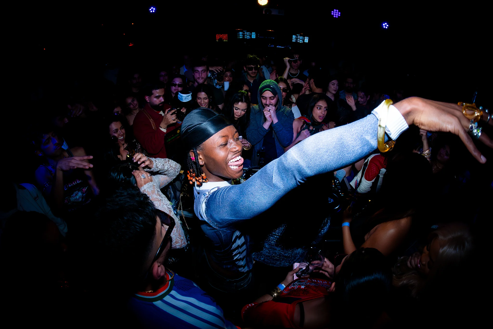 A performer reaches into the crowd at a packed Toronto nightclub event.