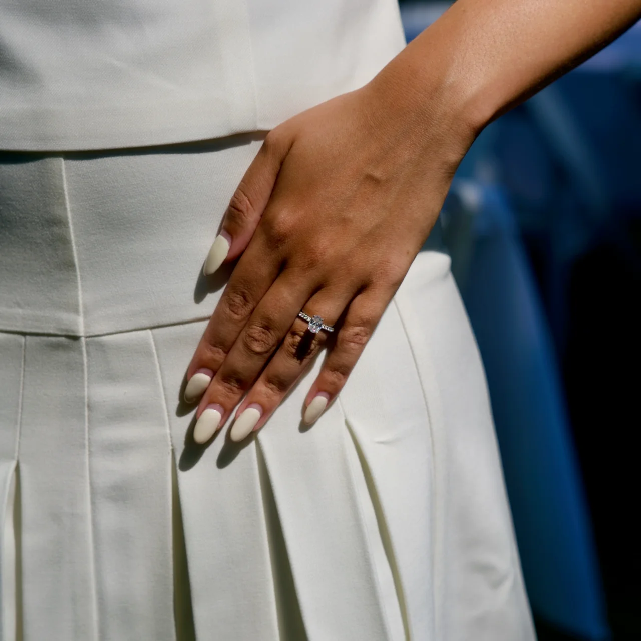A close detail of an engaged couple's hands, the ring visible as her hand rests on his shoulder.